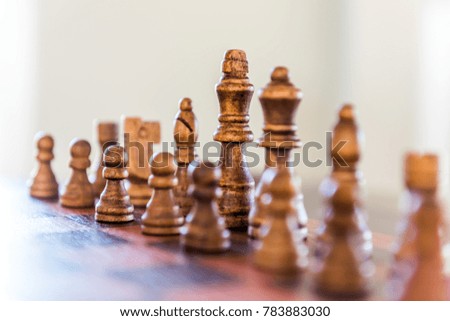 Closeup of chessboard with wooden pieces on table in sunlight, soft bokeh