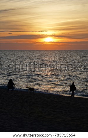 Sunrise image with people and do captured at the beach of Calella, Barcelona.             
