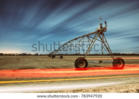 Long Exposure Night Photography of Farm Irrigation Equipment with Light Streak of Car Driving By