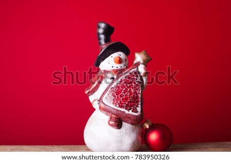 Little statue snowman with on wooden tabel and blur background photo of yellow lights. New Year time. Christmas theme
