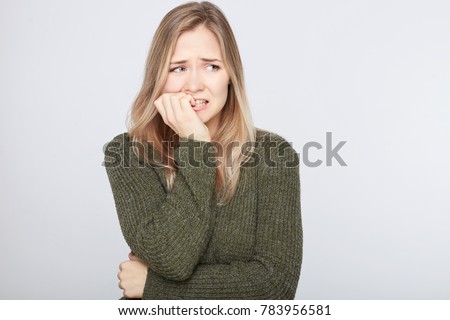 Indoor shot of horrified frightened hipster lady looking sideways, gestures actively and nervously, trembles from fear, has real phobia towards something, worries and being afraid of darkness. Royalty-Free Stock Photo #783956581