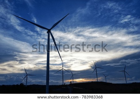 Windmills and sunset with cloudy blue sky.