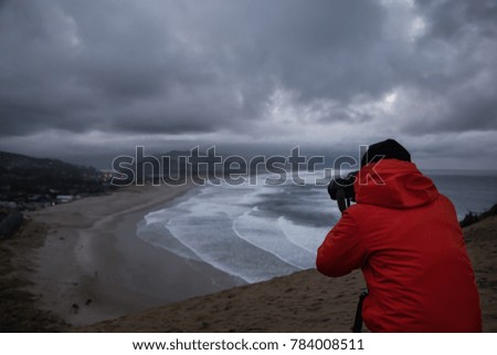 Photographer is taking pictures of the beautiful seaside view on the Oregon Coast. Taken in Cape Kiwanda, Pacific City, during a cloudy winter sunsrise.