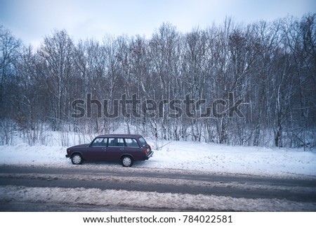 A car on a snowy road on a winter evening outside the city.