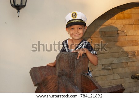 Boy child in captain's clothes smiles tenderly