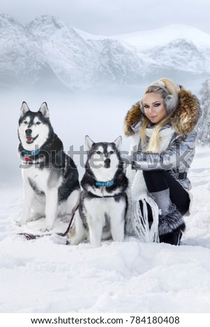 Beautiful young woman with Husky dog. Winter fashion. Snow, mountains and winter vacations. Royalty-Free Stock Photo #784180408