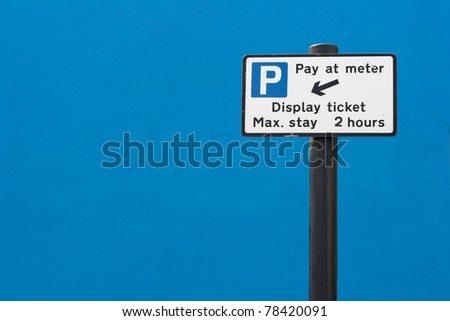 Pay at meter parking sign against a bright blue wall, UK