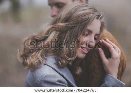 Young girl and guy with blond hair kisses, show love, affection. Boy and girl of European appearance with warm clothes, pictures with soft background bokeh blur fall. Concept of happiness, joy