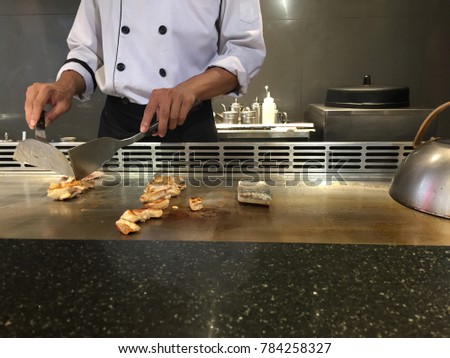 A chef grills chicken and sea bass.