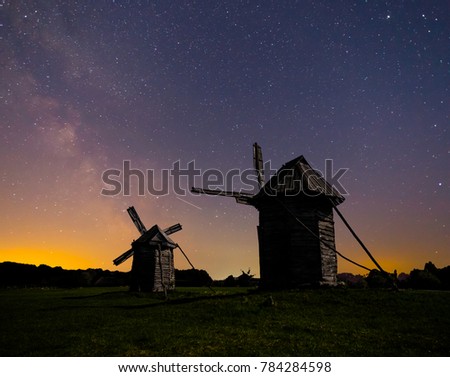 old medieval wooden windmill on a night sky background