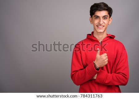 Studio shot of young handsome Persian teenage boy against gray background