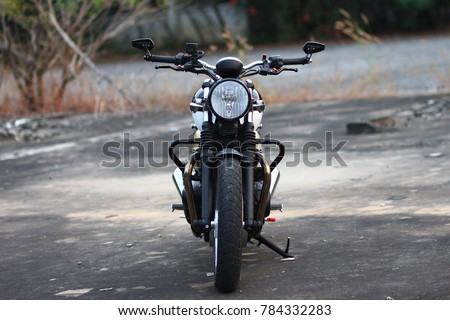 The picture is front view side of classic motorcycle standing on concrete floor.