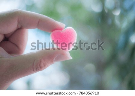A hand with a heart-shaped pink jelly sweets. Royalty-Free Stock Photo #784356910