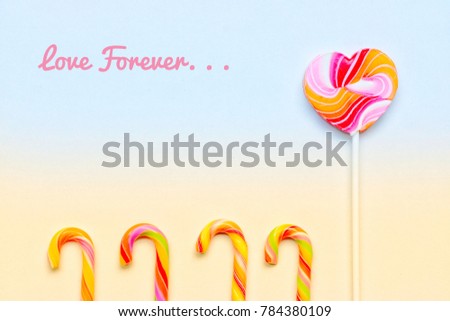 Heart-shaped lollipops and colorful candy canes on two-tone yellow and pale blue background with Love Forever wording.