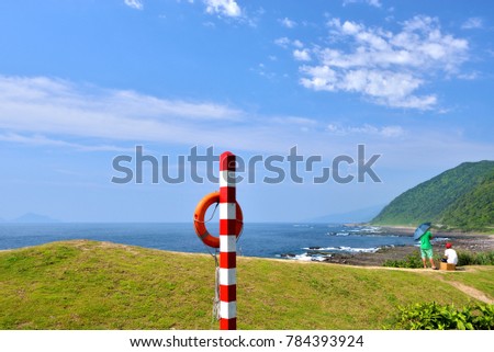 Standing on the lawn of the shores striking red and white safety warning post and life buoy.