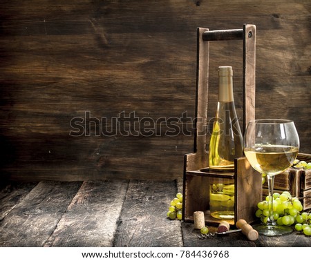 Wine background. White wine on a stand with branches of fresh grapes. On a wooden background.