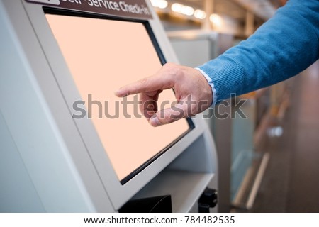 Confirm flight details. Close-up of male hands is using self-service check-in kiosk while standing at international airport building. He is registering on his airplane Royalty-Free Stock Photo #784482535