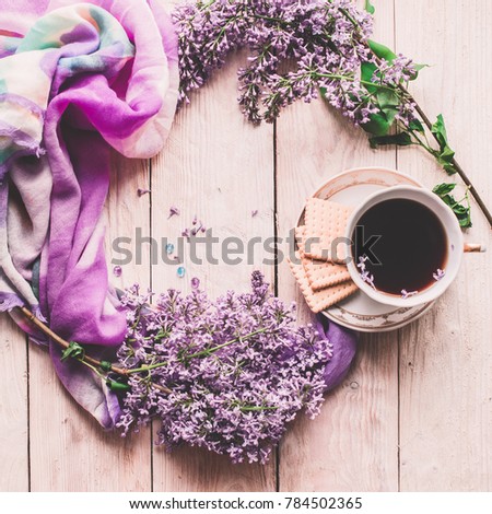 Morning cup of tee, cookies, and lilac flower on wooden table from above. Beautiful breakfast. Flat lay style with copy space