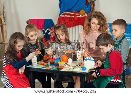 children draw at the table with the teacher. paint the mold with paints, hands in paint