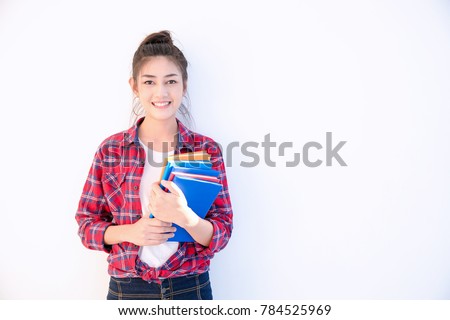 Young attractive asian student holding colorful books in her arm on white background. Smiling girl in colorful t-shirt hold many books. School girl with a lot books to read for homework. Royalty-Free Stock Photo #784525969