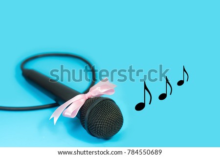 Microphone with pink ribbon and musical note on blue background.
