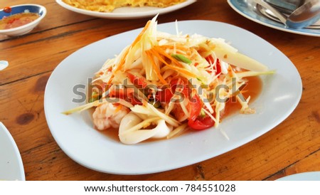 Papaya salad in white plate on wooden table, Food Thai style.
