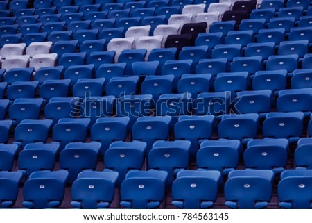 Blank old plastic chairs at the stadium. Number of empty seats in a small old stadium. Scratched worn plastic seats for fans