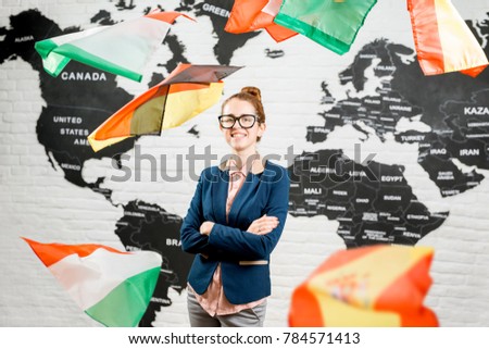 Portrait of a female travel agent dressed in the suit standing indoors surrounded by flying flags on the world map background