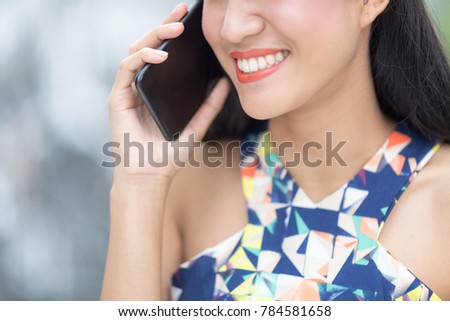 woman in white santa's hat  using smartphone against blur background.
