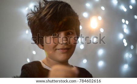 flame, child with flares of lights and Christmas lights in the background, party