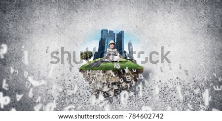 Young little boy keeping eyes closed and looking concentrated while meditating on island in the air among flying letters with gray wall on background. 3D rendering.