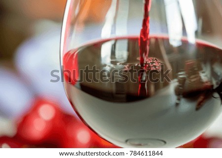 Pouring red wine into the glass against grape