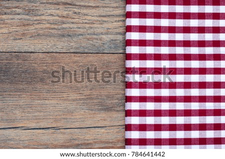 Tablecloth in white and red cage on wooden table. Studio Photo