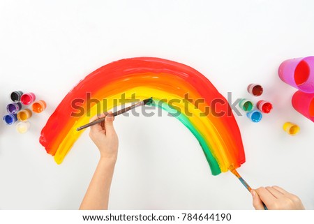 child's hand draws a rainbow on a white background