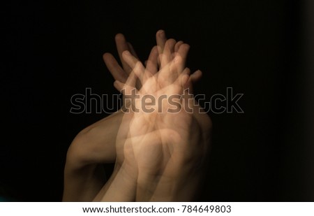 A lot of female fingers intertwine with each other against a dark background. multiple exposure