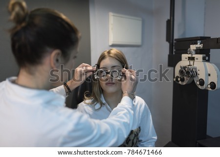 Woman in optometry test trying on trial frame to customer
