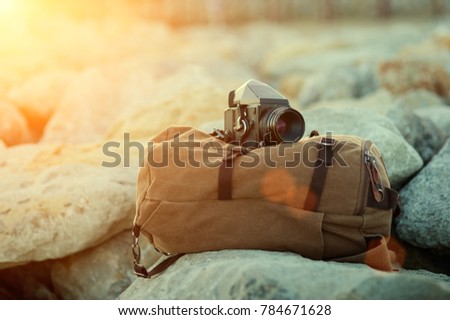 old film medium format camera lies on the rocks against the backdrop of a canvas vintage backpack for travel