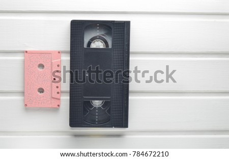 Video cassette and audio cassette on a white wooden table. Retro video and audio technology. Top view.