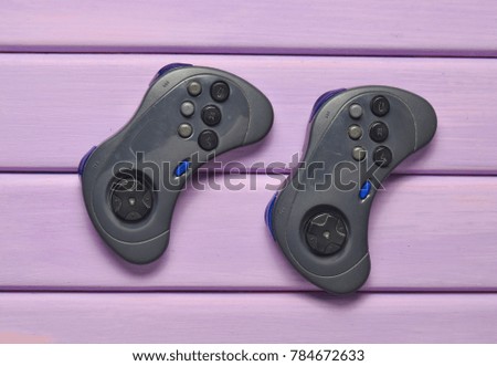 Two wireless gamepad on a purple wooden table. Top view.