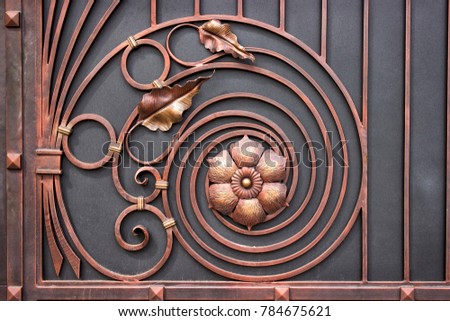 details of the structure and decoration wrought iron gate. Vintage metal copper color pictures. Decorative scroll and floral elements in the background.