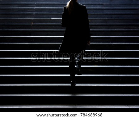 Urban walk : Blurry silhouette of young elegant woman climbing up the city street public stairs in the winter, alone , from behind
