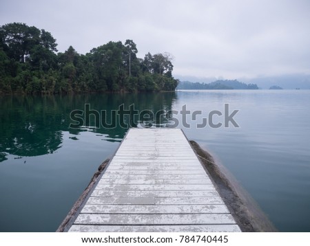 White wooden dock on a lake in the morning cool and foggy day.