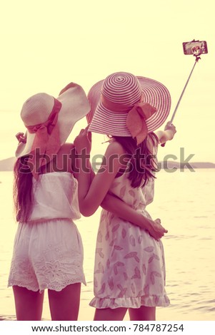 Silhouette of young beautiful tourist women selfie with smartphone during sunset at beach. Portrait of Happy traveler asian women using Smartphone for Selfie with Happy emotions. Vintage tone.