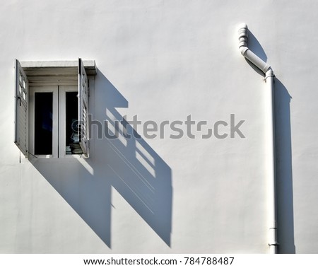 Old wooden window with white shutters and water pipe isolated on the white wall of a shop house in Chinatown, Singapore