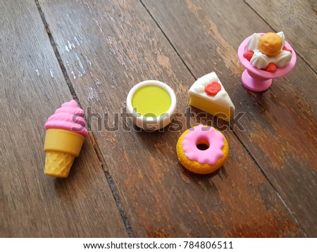 Tiny cute rubber of various dessert together ramdomly on wooden background