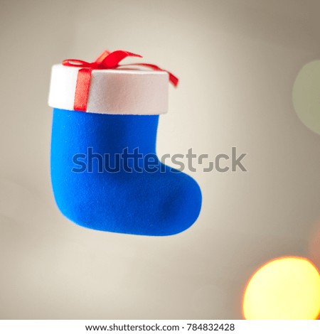 Jewelery in a gift box in the form of a blue Christmas sock against the backdrop of New Year's lights, selective focus
