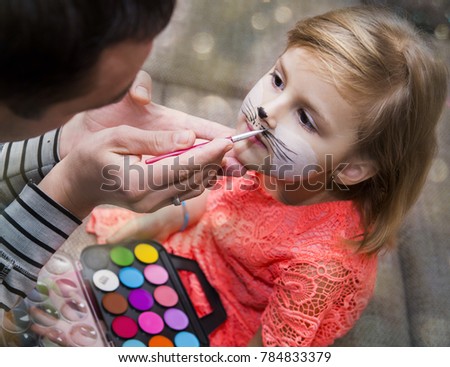 Process drawing a face painting on a child's face