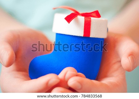 Gift wrap in the form of a blue Christmas sock in the hands of a child, a New Year's surprise
