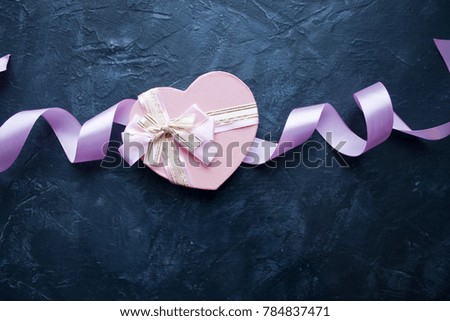 Valentine's Day greeting card. Gift in shape of heart, ribbons on dark blue background. Copy space.
