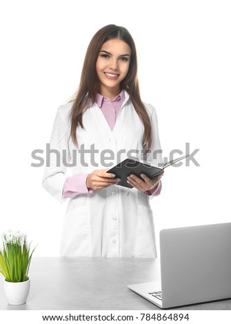 Young female pharmacist with notebook on white background